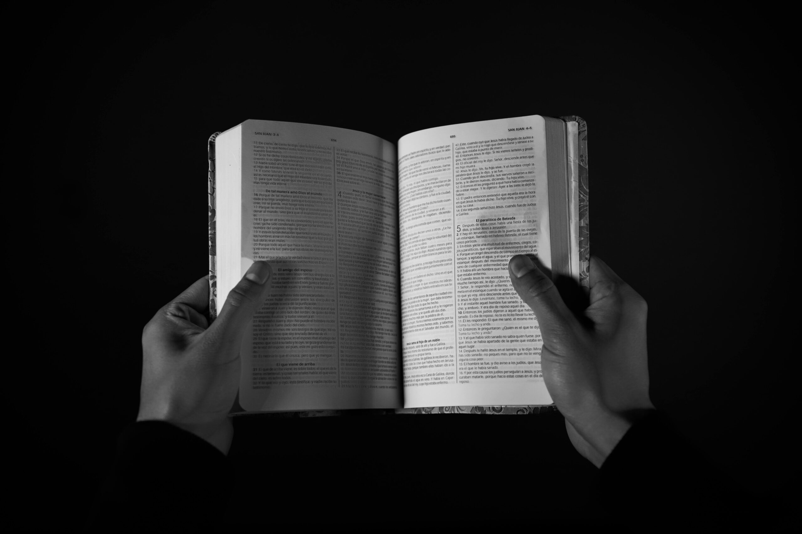 Black and white image showcasing hands holding an open book, symbolizing knowledge.